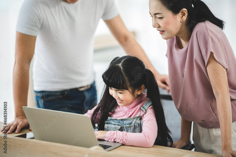 Wall mural Asian children learning from home, homework learning with father and mother together in daughter family by laptop technology people, happy girl in online education lifestyle