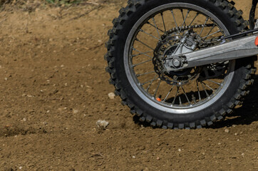 Fototapeta premium The wheel of a racing motocross motorcycle rides along the race track at high speed, stones and dust fly out from under the wheel