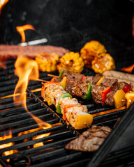 Closeup on grilling sausages and meat with flame on a barbecue