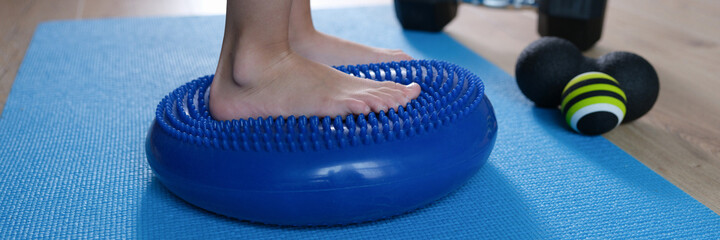 Child foot is resting on blue massage balancing cushion closeup