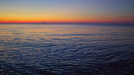 Sea sunset reflecting at water surface in evening dawn. Calm blue ocean waves
