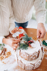 Gingerbread house and women's and man's hands in sweater, the concept of preparation for the Christmas holidays.