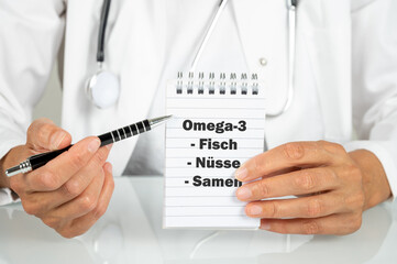 Ein Arzt zeigt auf einen Notizblock auf den Omega 3 Fettsäuren in Fisch, Nüssen und Samen steht