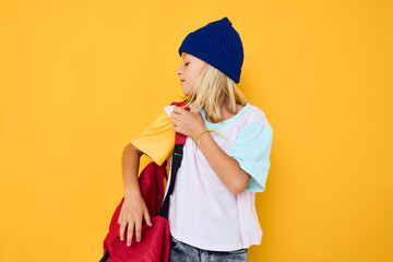 girl in a hat with a backpack school yellow background