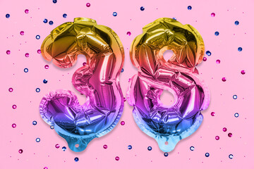 Rainbow foil balloon number, digit thirty eight on a pink background with sequins. Birthday greeting card with inscription 38. Top view. Numerical digit. Celebration event, template.