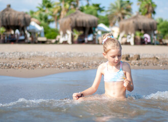 Little girl playing on the beach by the sea