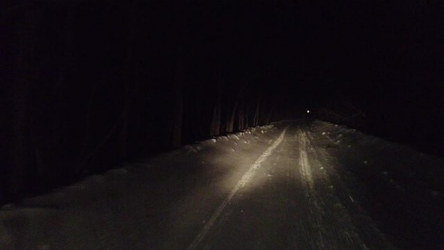 Steadicam shot of winter nght ride from inside car in snow-storm, headlights and snow only