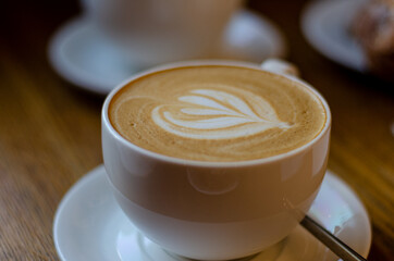 a beautiful pattern on coffee foam made by a barista in a white glass with hot latte or cappuccino coffee