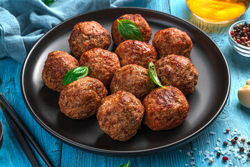 Fried Meatballs with basil close-up on a blue background.