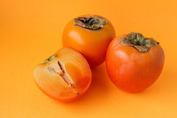 Ripe juicy persimmon on an orange background