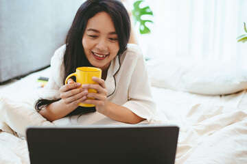 young Asian woman using laptop computer to business online work, female freelance working from home by using internet cyberspace communication technology for businesswoman job