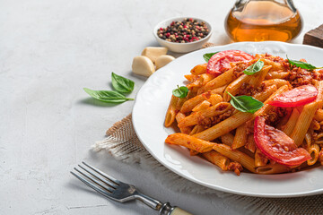 Penne pasta with bolognese sauce with fresh basil close-up on a gray background.