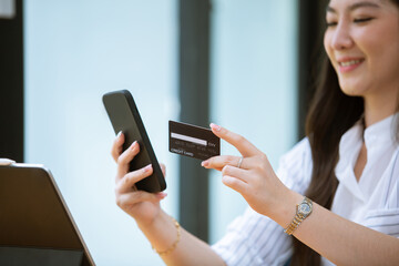 Asian woman enjoying using credit card phone and computer at her house