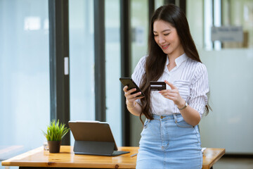 Asian woman enjoying using credit card phone and computer at her house