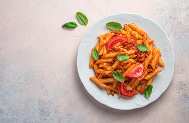 A plate with pasta and bolognese sauce on a light pink background.