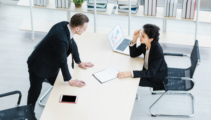 Millennial Caucasian successful thoughtful businessman and businesswoman colleague teamwork in formal suit working togeterh discuss brainstorming solution ideas at company workplace