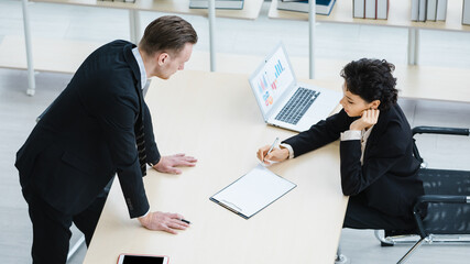 Millennial Caucasian successful thoughtful businessman and businesswoman colleague teamwork in formal suit working togeterh discuss brainstorming solution ideas at company workplace