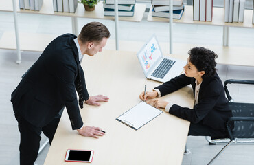 Millennial Caucasian successful thoughtful businessman and businesswoman colleague teamwork in formal suit working togeterh discuss brainstorming solution ideas at company workplace