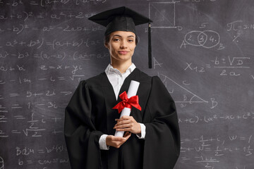 Female graduate student with diploma in front of a blackboard
