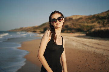 woman walks along the sandy shore in a black swimsuit sun tropics