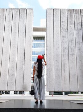 Vertical Lines. Full Length Of A Young Girl Standing In Front Of High Walls