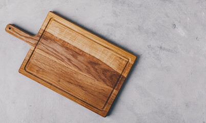 A wooden cutting board on gray concrete stone background. Top view, copy space.