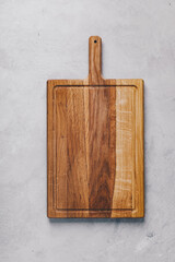 Fototapeta premium A wooden cutting board on gray concrete stone background. Top view, copy space.