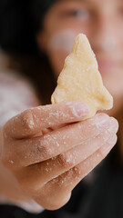 Selective focus of child holding cookie dough with tree shape in hands preparing homemade traditional gingerbread enjoying cooking dessert in culinary kitchen. Girl enjoying christmas holiday