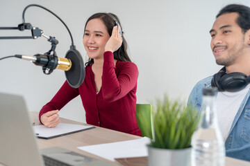 Asian Radio Host Podcast in Studio. Male and female speakers talk through mics and cameras on their...