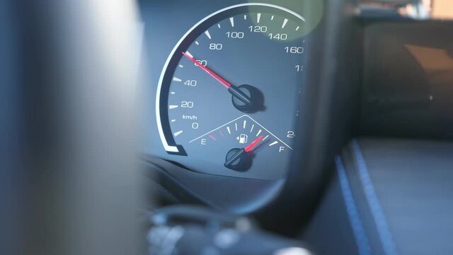 Bright red arrow on speedometer located on dashboard of foreign car shows permitted speed of car and short hand indicates petrol level, closeup