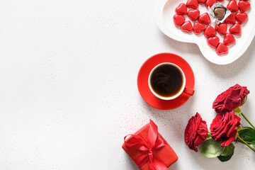 Obraz na płótnie Canvas Valentine's day coffee, red gift and red roses on white background. Romantic greeting card for dating. View from above. Copy space.