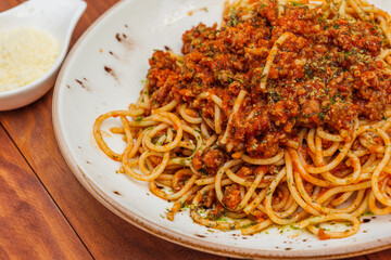 Spaghetti bolognese - pasta with minced meat and vegetables. Horizontal side view on wooden background
