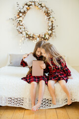 Two little sisters near the Christmas tree.