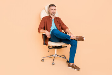 Fototapeta premium Full length photo of bossy smart partner middle-aged guy sit leather chair isolated over pastel beige color background