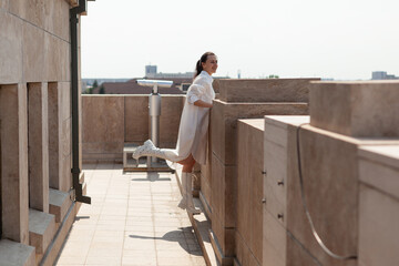 Woman tourist standing on tower terrace enjoying seeing landscape of metropolitan city during summer vacantion. Urban buildings from observation point. Landscape with skyscraper rooftop