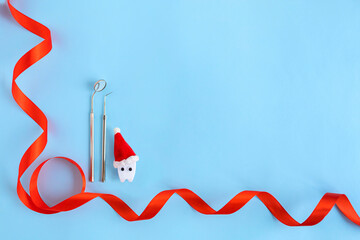 dental christmas, new year concept. toy tooth in red santa hat, medical instrument for examining...