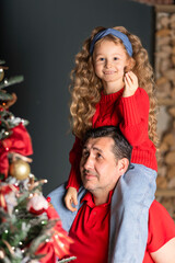 girl and man decorating Christmas tree in eve winter holiday. toddler kid sitting on shoulders of dad. concept daughter father. Happy family new year.  soft focus