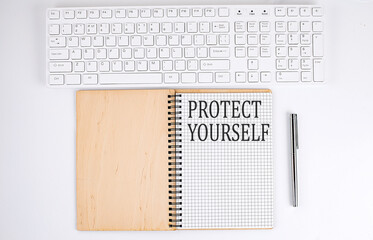 PROTECT YOURSELF text on the notebook with keyboard on white background