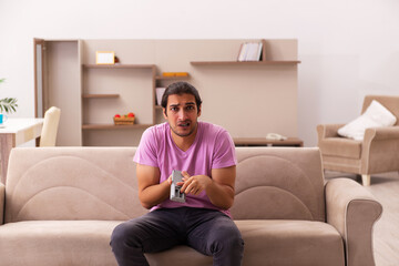 Obraz premium Young man watching tv at home during pandemic