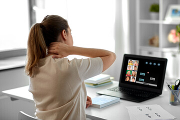 distant education, remote job and health concept - tired female teacher having online class with group of students on laptop computer and touching her aching neck at home office