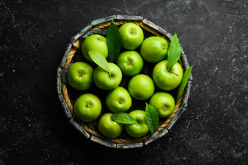 Fruits. Fresh juicy green apples on a tray. Rustic style. On a black stone background.