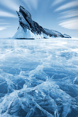 Sibirische Winterlandschaft. Insel Ogoy im Bakalsee. Transparente gemusterte Eisfläche und mächtiger Felsen. Frostiges blaues Bild.