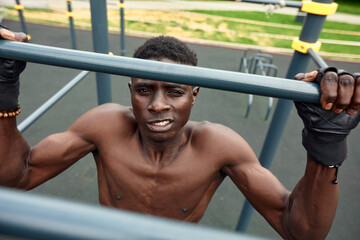 Portrait of black male working out outdoors in a park. He is using a chest machine.