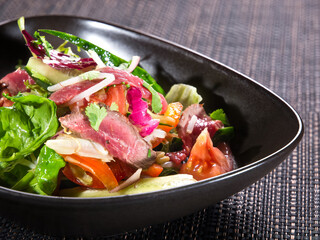 Salad with beef slices, green fresh lettuce, cucumbers, tomatoes and onion