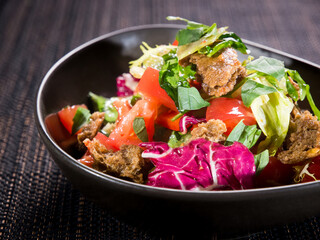 vegetarian salad with fresh green fresh lettuce, red cabbage, tomatoes and fried bread crackers in a bowl