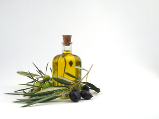 Faceted bottle with olive oil and olive branch with black olives on white background. Copy space