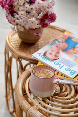 Cup of fresh coffee, magazines and beautiful bouquet on wooden stands. Good morning