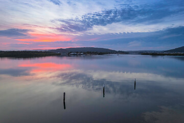 Soft and peaceful sunrise aerial waterscape with clouds and reflections