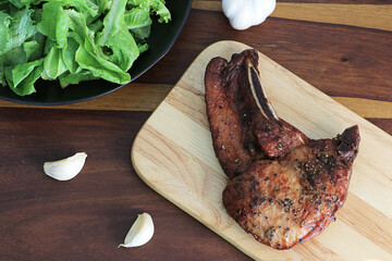 Grilled T-bone steak on cutting board.