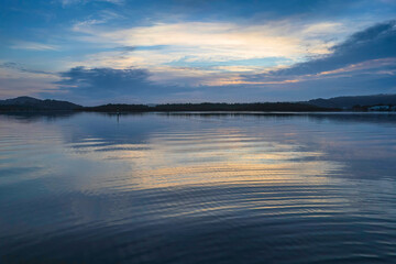 Soft and peaceful sunrise aerial waterscape with clouds and reflections